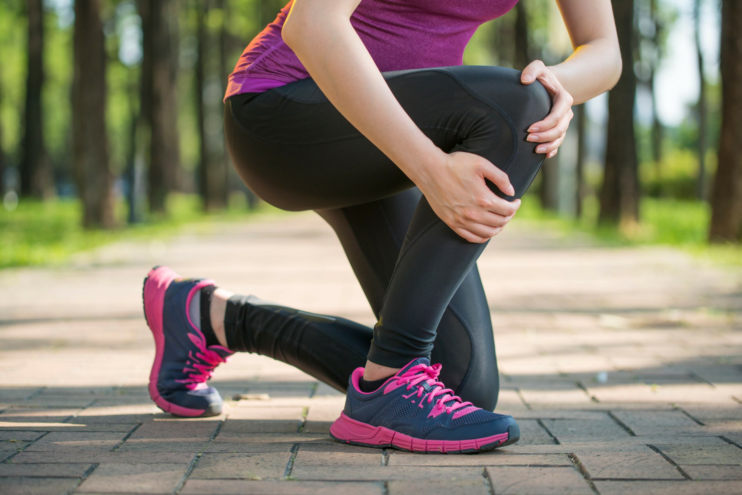 Woman Grabbing Knee in Pain While Jogging